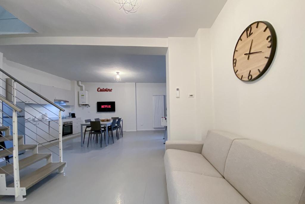 salon z kanapą i zegarem na ścianie w obiekcie [Affori] - Appartamento funzionale vicino metro w Mediolanie