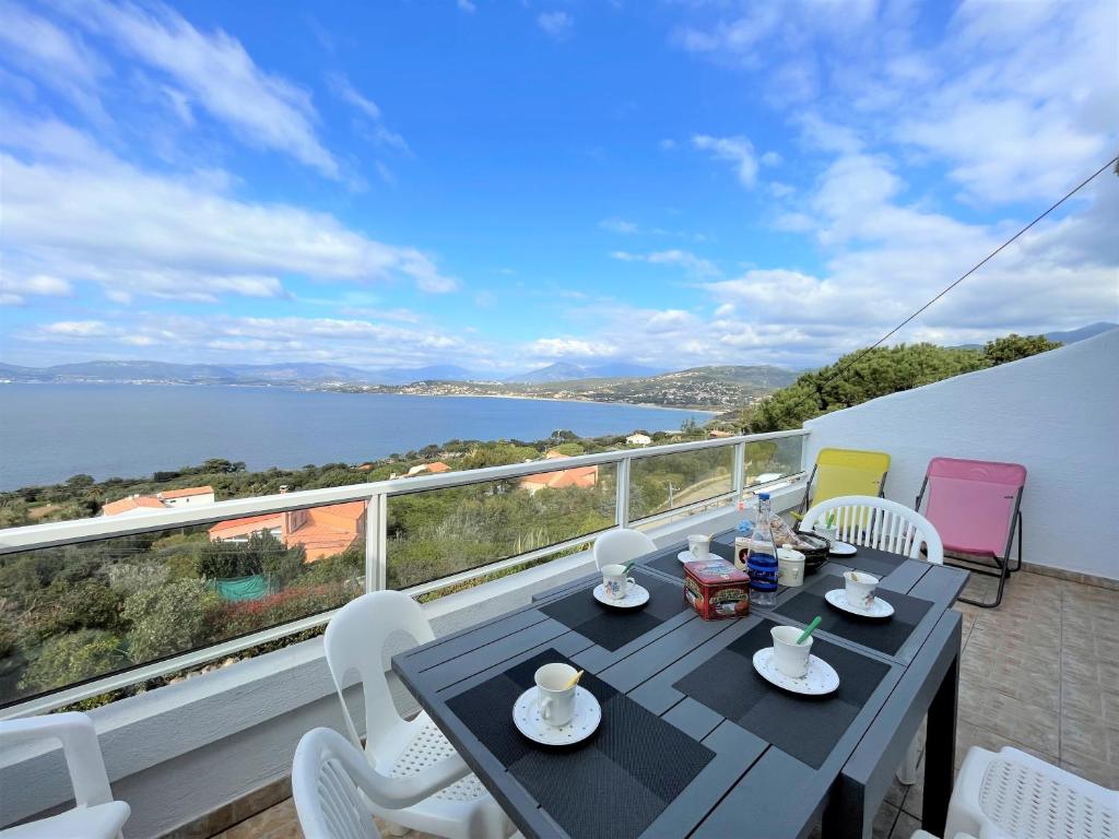 une table et des chaises sur un balcon avec vue sur l'eau dans l'établissement Appartement A Stagnola PORTICCIO, à Porticcio
