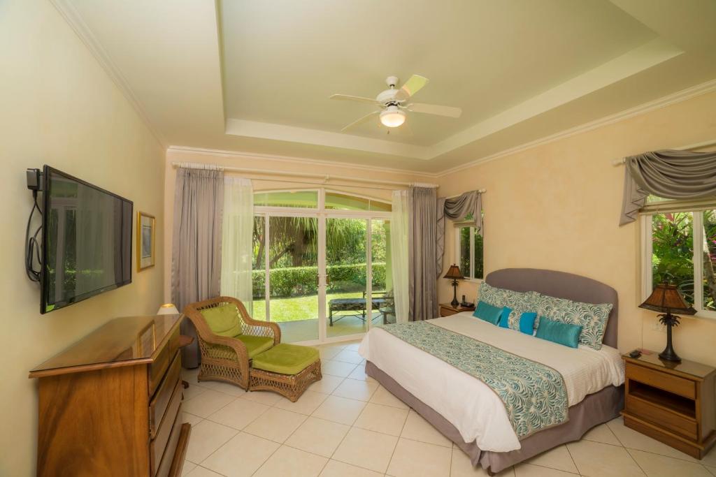 a bedroom with a bed and a television and a chair at Los Suenos Resort Colina 9E in Herradura