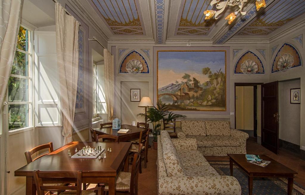 un soggiorno con divano, tavoli e un dipinto di B&B Villa La Perla a Lucca