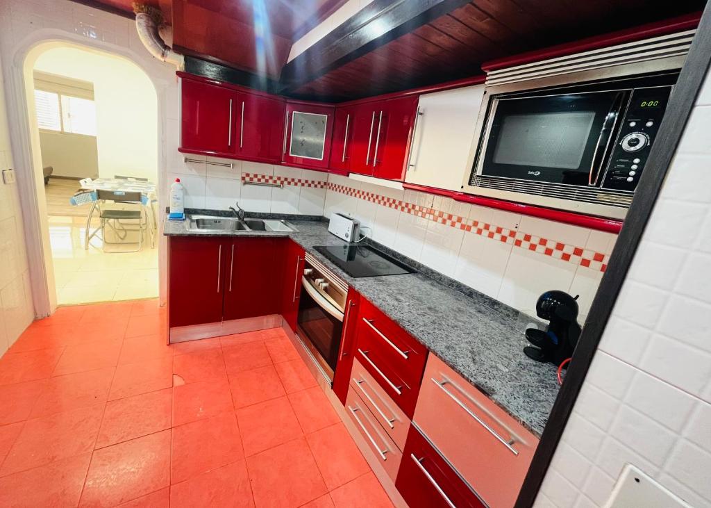 cocina roja con fregadero y microondas en La Calzada Apartment, en Tafira