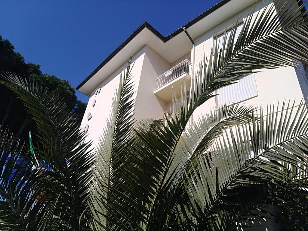 a white building with palm trees in front of it at MILANO in Marina di Pietrasanta