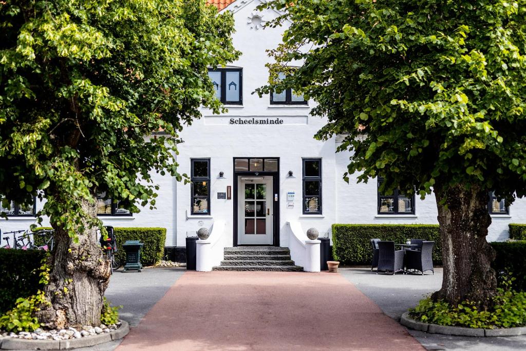 ein weißes Gebäude mit Bäumen davor in der Unterkunft Hotel Scheelsminde in Aalborg