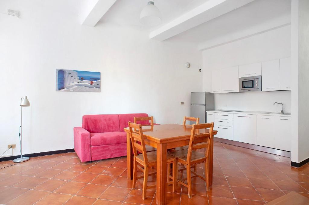 kuchnia i jadalnia ze stołem i różową kanapą w obiekcie Casa Terrazzino Bianca w mieście Levanto