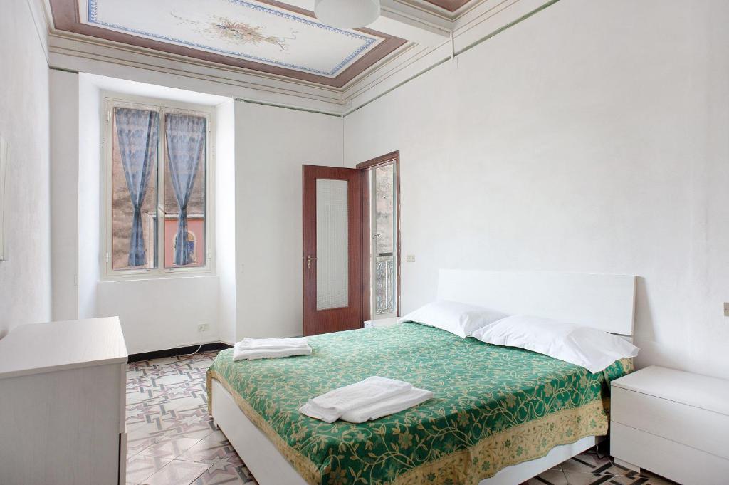 a white bedroom with a bed with a green blanket at Casa Terrazzino Bianca in Levanto