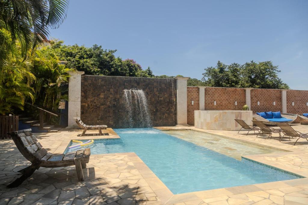 una piscina con cascada, mesa y sillas en Pousada La Dolce Vita, en Búzios