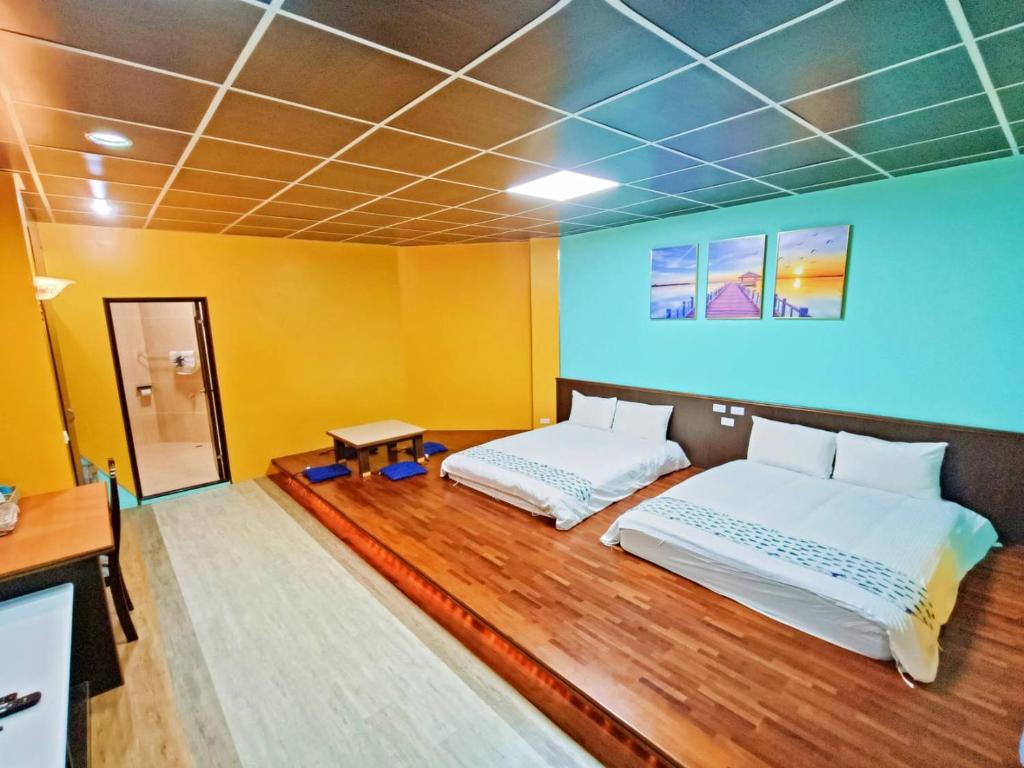 two beds in a room with yellow walls and wooden floors at 恆春古城親子民宿 in Hengchun South Gate