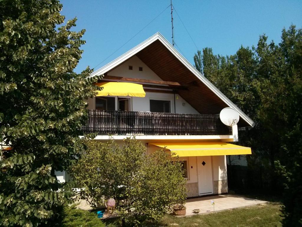 ein weißes Haus mit einem Balkon und einem Baum in der Unterkunft Appartments Hungaroland in Balatonberény
