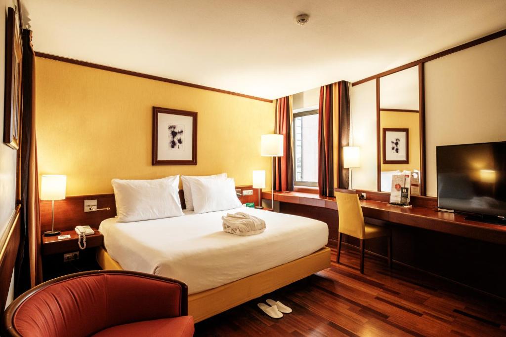 una camera d'albergo con letto, scrivania e TV di Holiday Inn Lisbon-Continental, an IHG Hotel a Lisbona