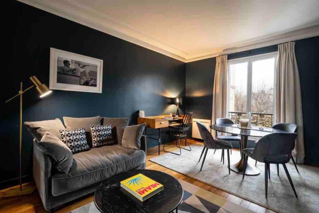 een woonkamer met een bank en een tafel bij Appartement cosy cœur de Neuilly-sur-Seine in Neuilly-sur-Seine