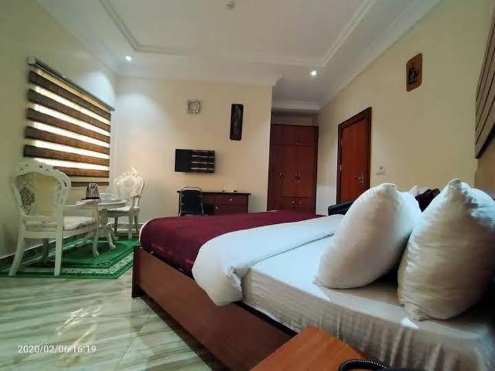 a bedroom with a large bed and a table at Alim Royal Hotel in Jahi