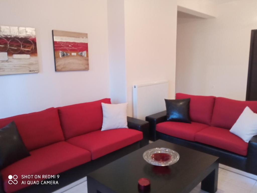 a living room with red couches and a table at serres center in Serres