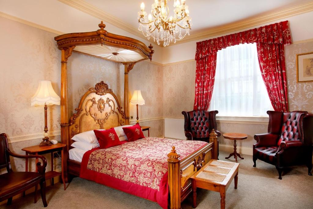a bedroom with a canopy bed and two chairs at The Royal Lion Hotel in Lyme Regis