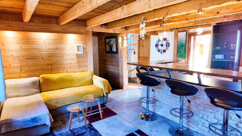 a living room with a yellow couch and a bar at Le Grenier 1821 - Mini chalet - Centre village - AravisTour in Saint-Jean-de-Sixt