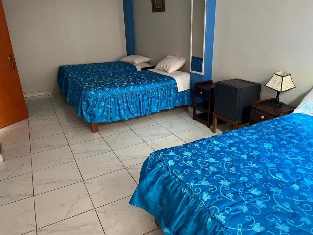 2 bedden in een kamer met een blauw dekbed bij Posada de Percybal Mirador in Puno