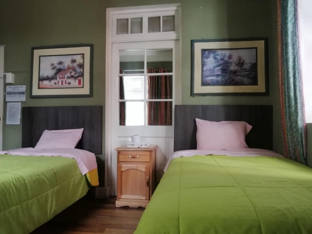 twee bedden in een kamer met groen en roze bij Posada Casa Real in Huancayo
