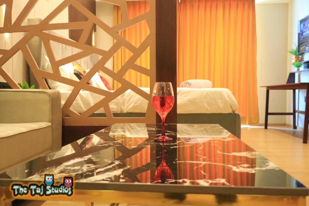 a wine glass sitting on a glass table in a living room at Super Luxurious Stay at Biggest Mall Galaxy Blue Sapphire,Bar, Club, US Cinemas, Food Court, SuperMart etc, by Taj Studios in Ghaziabad