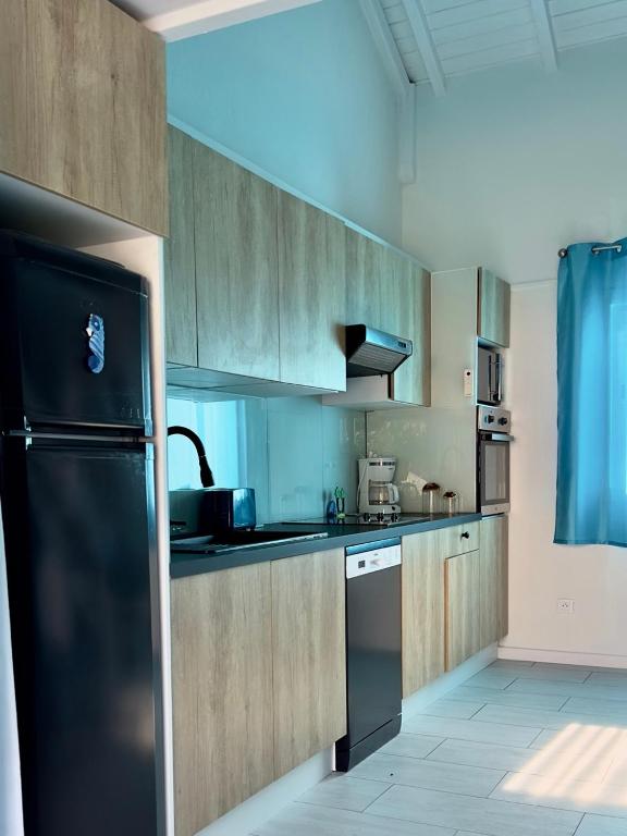 a kitchen with wooden cabinets and a black refrigerator at Sun Caraibes in Orient Bay