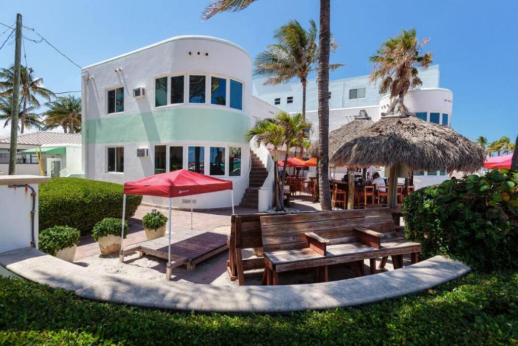 a house with a bench and tables and umbrellas at Walkabout 2 Oceanfront Suite on Hollywood Beach in Hollywood