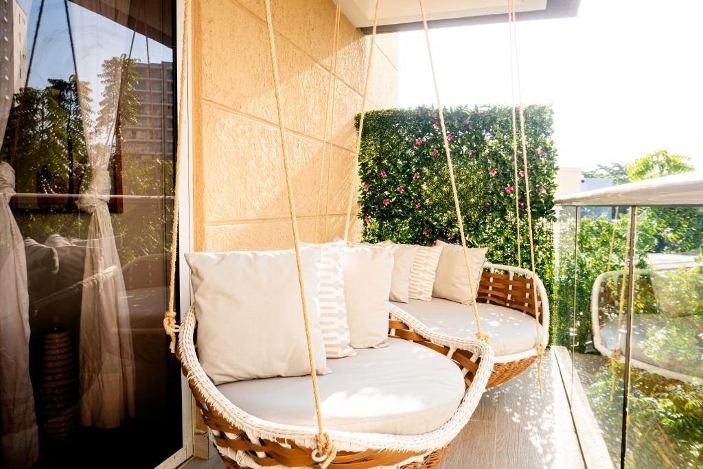 een schommel op de veranda met witte kussens op een balkon bij Pet-Friendly Pool Retreat with Luxury Hot Showers in Santa Marta
