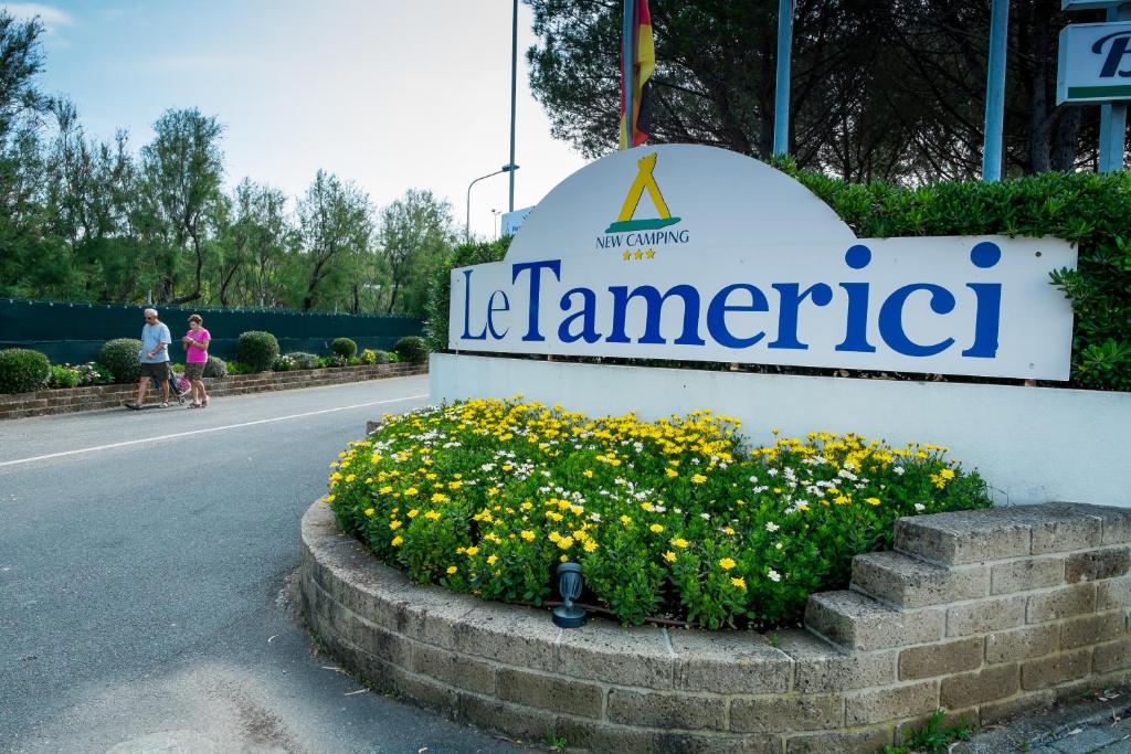 a sign for a hotel with flowers in the street at New Camping Le Tamerici in Marina di Cecina