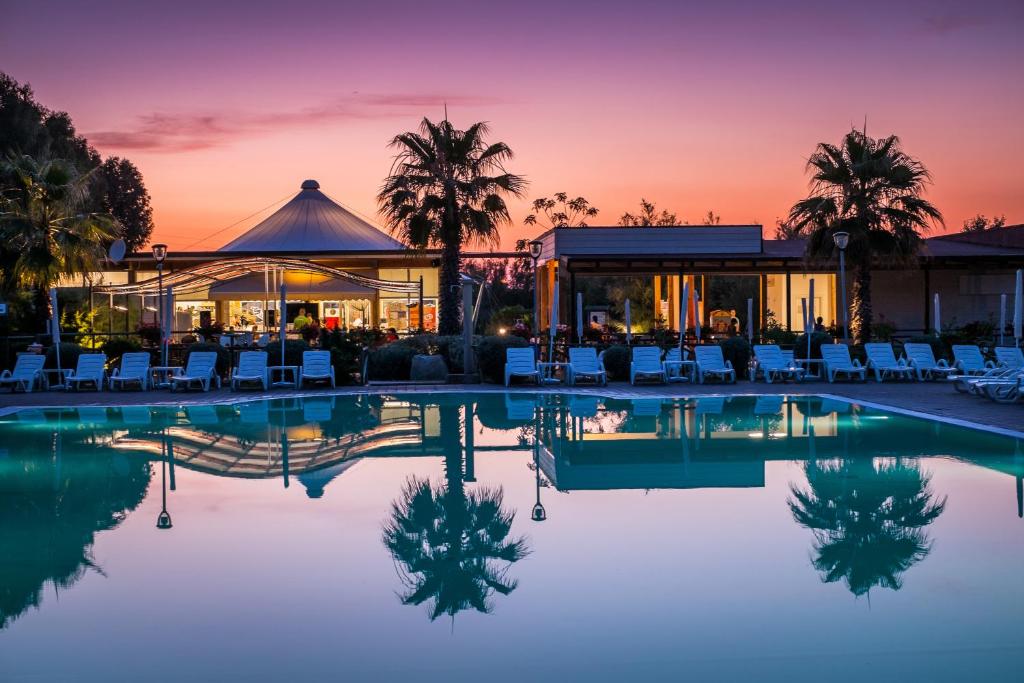 Blick auf den Pool in einem Resort bei Sonnenuntergang in der Unterkunft New Camping Le Tamerici in Marina di Cecina
