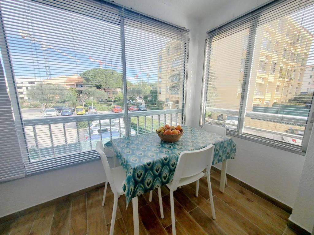 une salle à manger avec une table, des chaises et des fenêtres dans l'établissement Studio rénové à deux pas de la plage de Sainte Asile à Pin Rolland, à Saint-Elme
