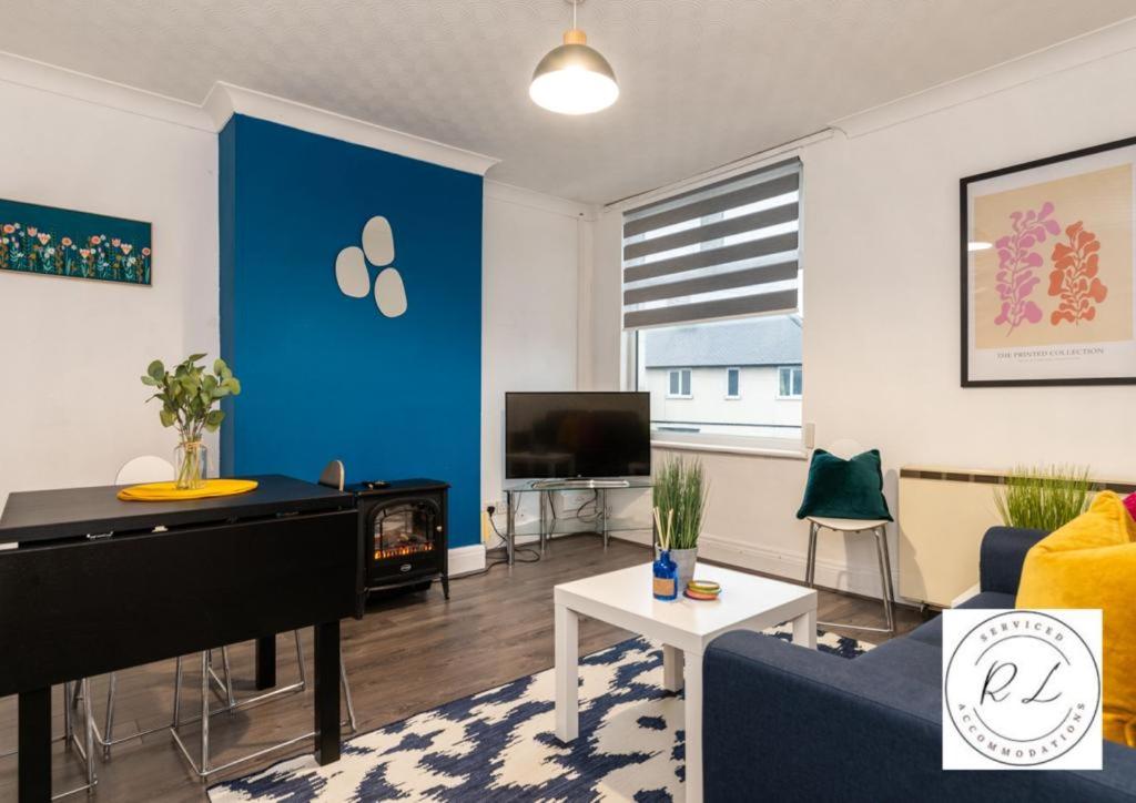 een woonkamer met een blauwe muur en een piano bij Modern Apartment in Wigston with Free Parking! in Wigston Magna