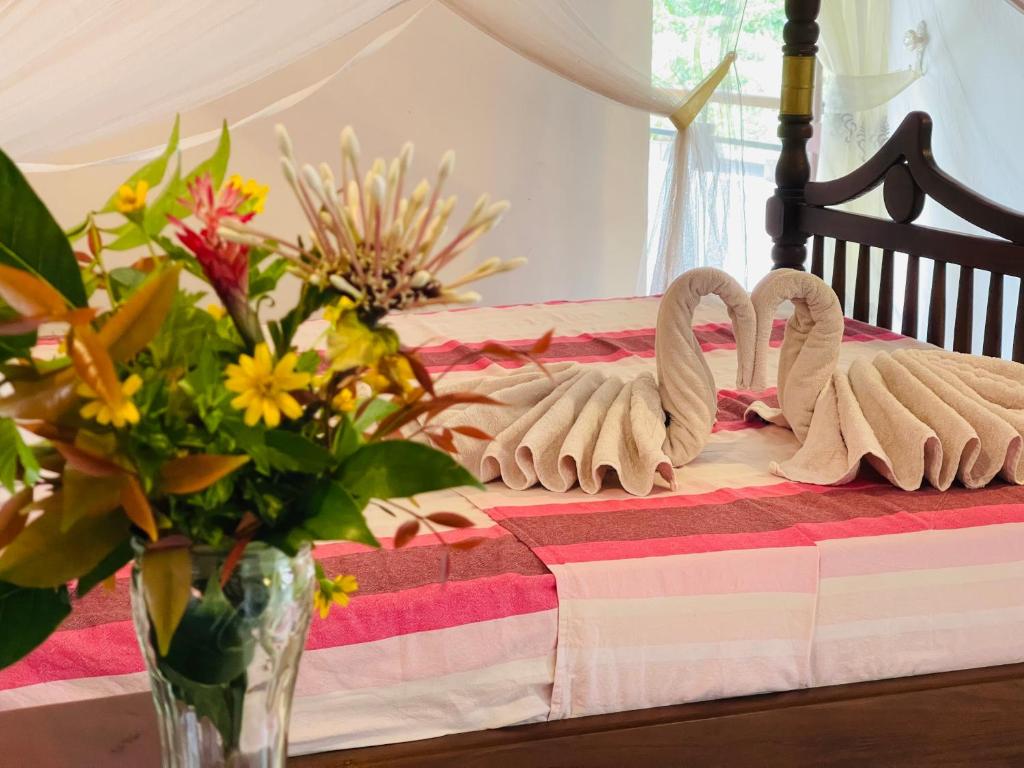 two swans sitting on a bed with a vase of flowers at Su Yu villa in Unawatuna