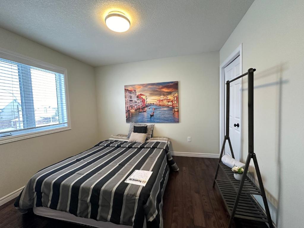 1 dormitorio con 1 cama con una pintura en la pared en Room in Kitchener I, en Kitchener