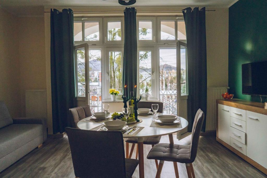 a dining room with a table with chairs and a window at Apartamenty ABRACADABRA in Ustroń