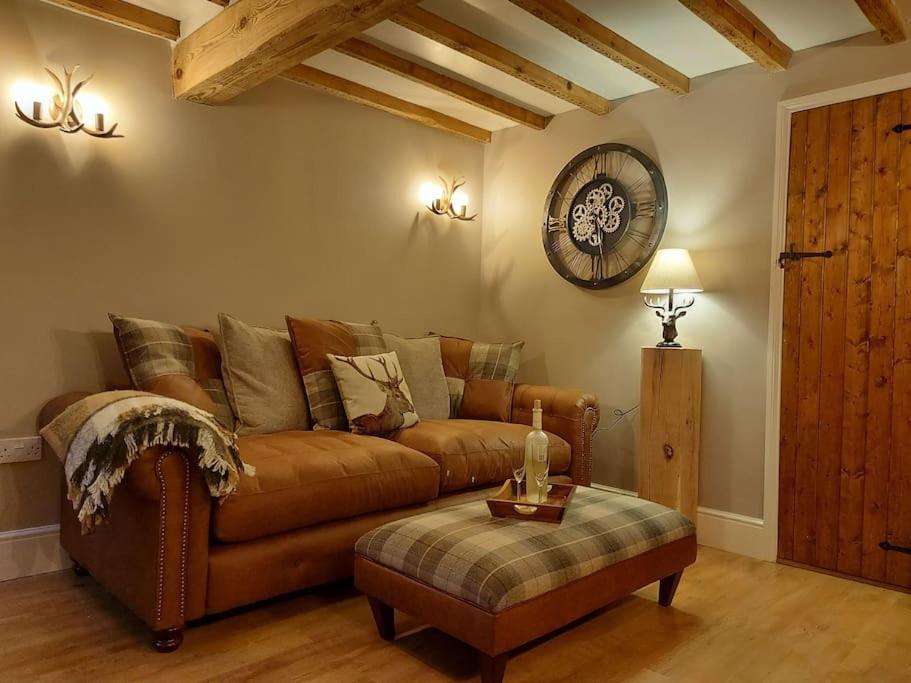 a living room with a brown couch and a table at Woodys Retreat Cosy One Bed Cottage in Belper