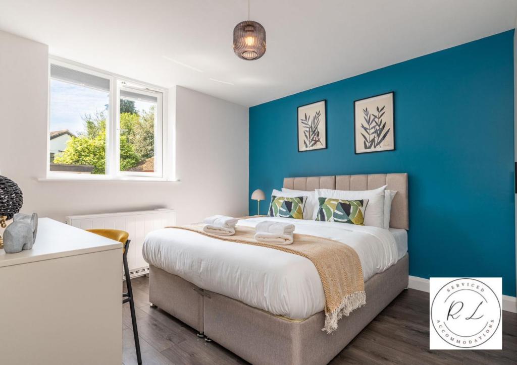 a bedroom with a large bed with a blue wall at Comfy Modern 2 Bed near Glenfield Hospital, sleeps up to 6 in Glenfield