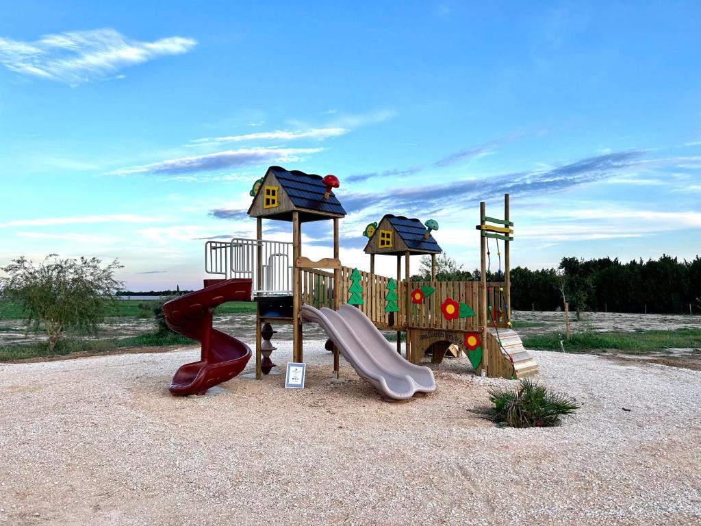 un groupe d'équipements de jeux dans un parc dans l'établissement Gîte à la ferme avec Piscine, à Arles
