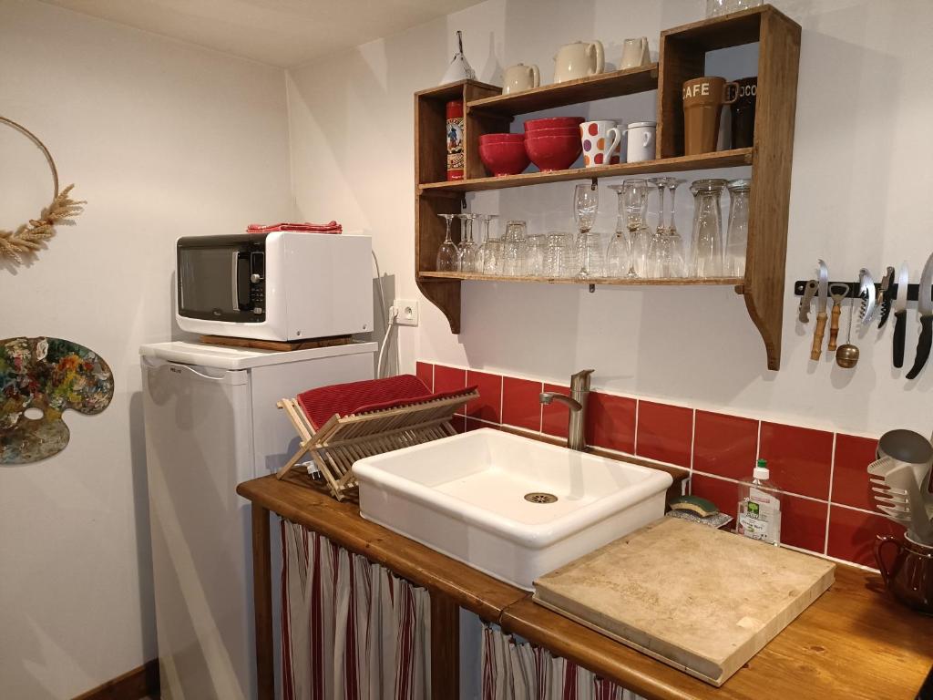 a kitchen with a sink and a microwave on a refrigerator at Lovely cottage in Honfleur center in Honfleur
