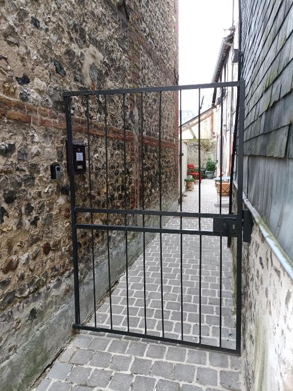 a gate in a brick wall with a stone walkway at Lovely cottage in Honfleur center in Honfleur