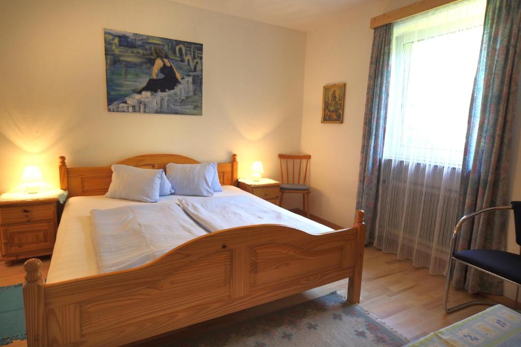 a bedroom with a large wooden bed with white sheets at Gästehaus Lienharterhof in Obertilliach