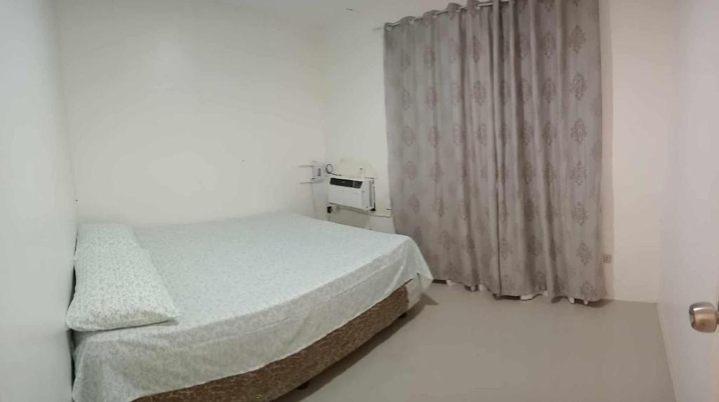 a white bedroom with a bed and a window at Casita de Zacate in Cagayan de Oro