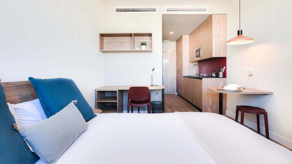 Cet appartement comprend une chambre avec un lit blanc et une cuisine. dans l'établissement Livensa Living Studios Madrid Alcobendas, à Alcobendas