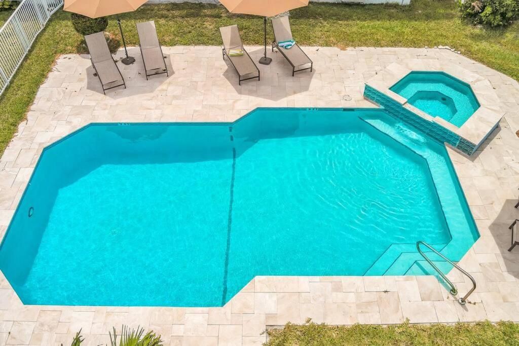 een blauw zwembad met 2 stoelen en een parasol bij 1 bedroom tropical pool house in Hallandale Beach