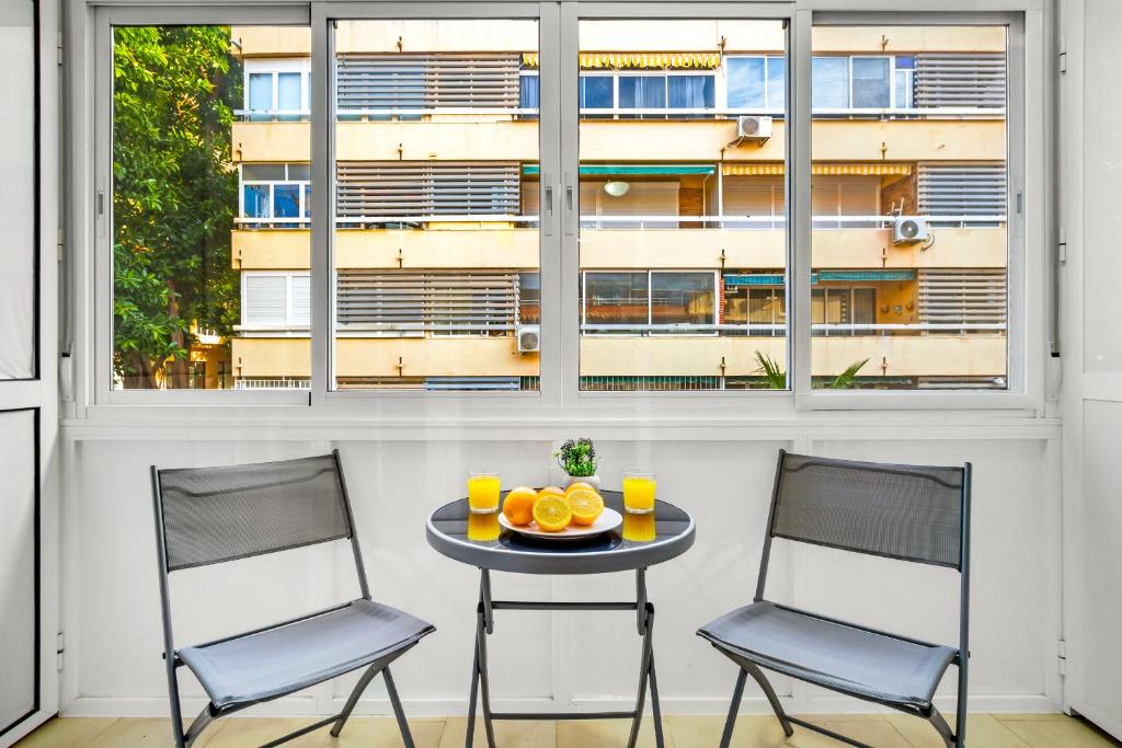 two chairs and a table in a room with a window at Los Nidos 603 By IVI Real Estate in Torremolinos