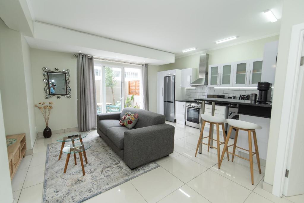 a living room with a couch and a kitchen at The Healing hideaway near St Georges Hospital in Port Elizabeth