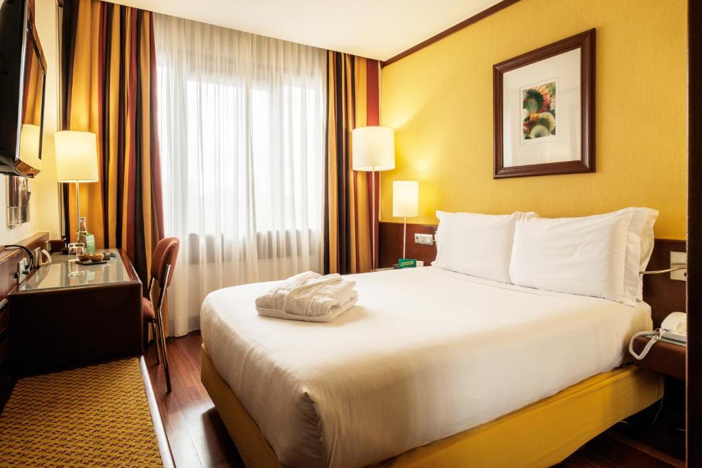 A traditional guest room centered on a large bed with a small work area by the window.