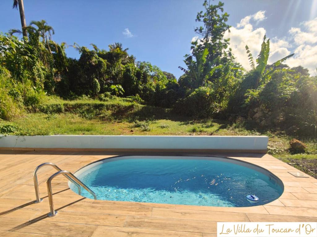 einen Pool mit einem Stuhl auf einer Terrasse in der Unterkunft La Villa du Toucan d'Or, au cœur de la Guadeloupe in Petit-Bourg