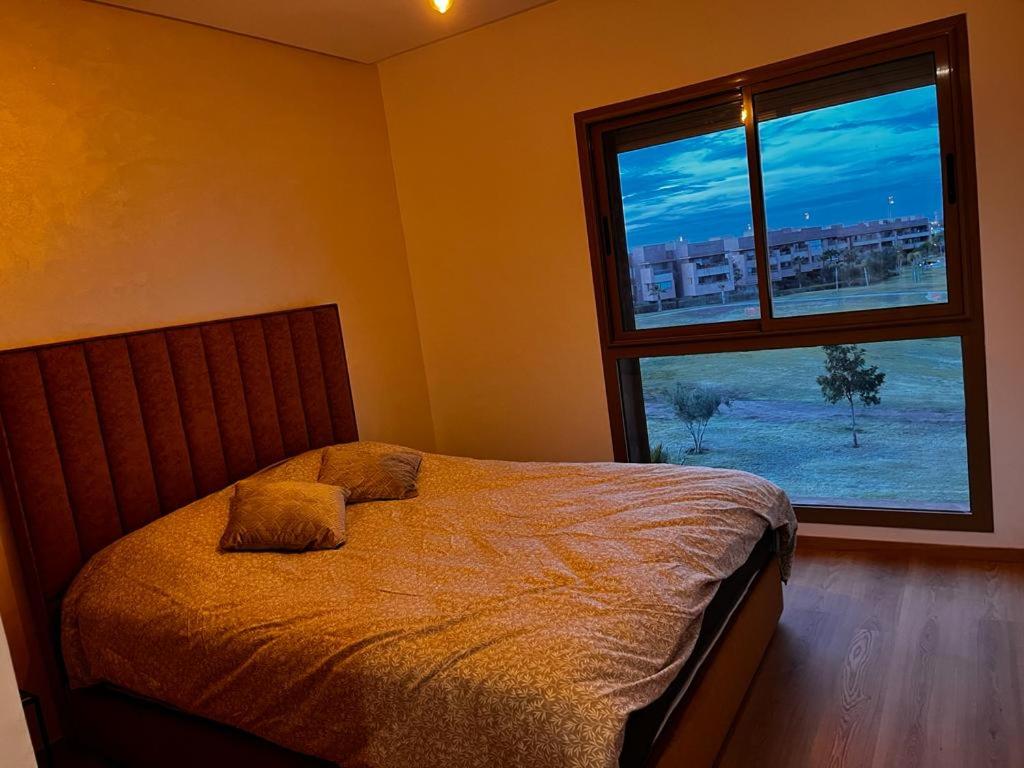 a bedroom with a bed and a large window at Appartement Golf City Prestigia Marrakech in Marrakesh