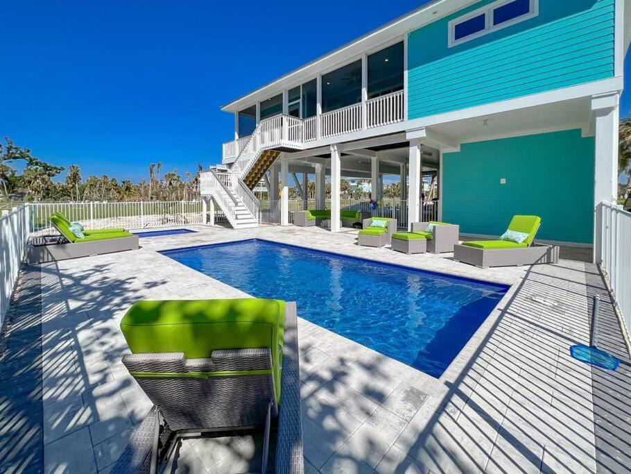 uma piscina com cadeiras e uma casa em Island Retreat: Your Exclusive Oasis Awaits em North Captiva