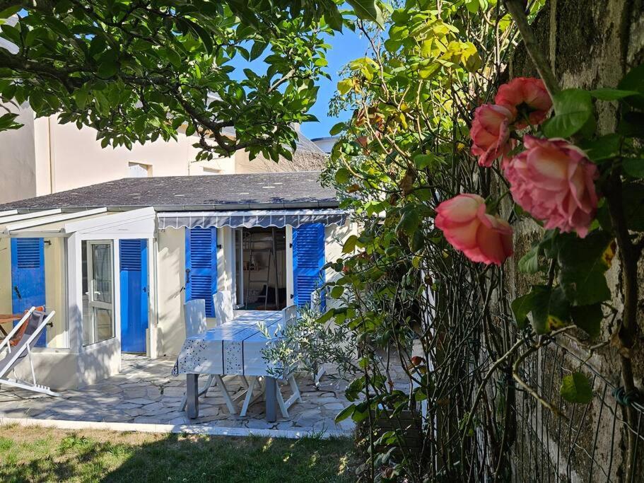 een blauw-wit huis met een tafel en bloemen bij Maisonnette des Sables Blancs avec jardinet Tréboul in Douarnenez