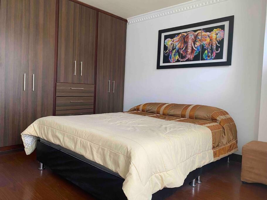 1 dormitorio con 1 cama grande y una pintura en la pared en Elegante apartamento Ipiales, en Ipiales