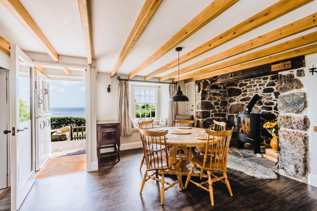 a dining room with a table and chairs and a stone fireplace at Prospect House in Coverack