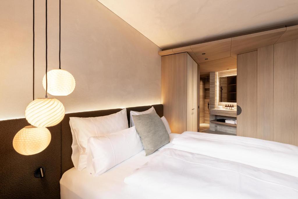a bedroom with a large white bed with two lights at Domenigs Luxury Apartments in Fiss